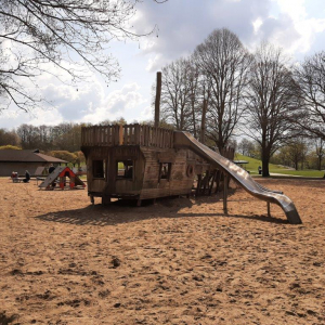 Das Bild zeigt ein großes Schiff auf Holz, das umgeben von Sand als Spielmöglichkeit für Kinder dient.