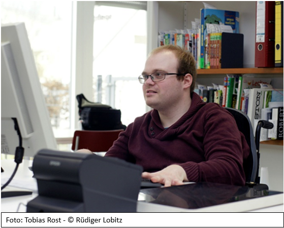 Das Bild zeigt Tobias Rost an seinem Schreibtisch
