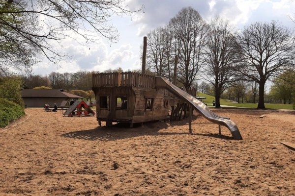 Das Bild zeigt ein großes Schiff auf Holz, das umgeben von Sand als Spielmöglichkeit für Kinder dient.